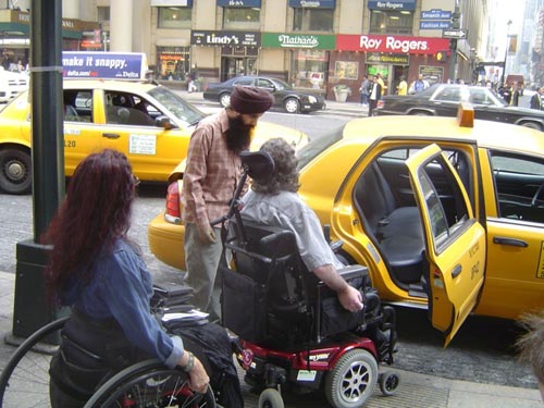 Picture of two people in wheelchairs in front of a cab