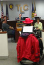 photo of far view of Jean Ryan speaking at a podium at TLC hearing