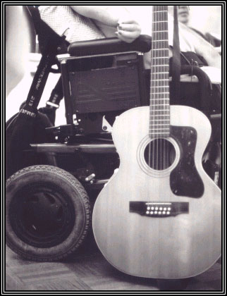 Photo of guitar next to a motorized wheelchair
